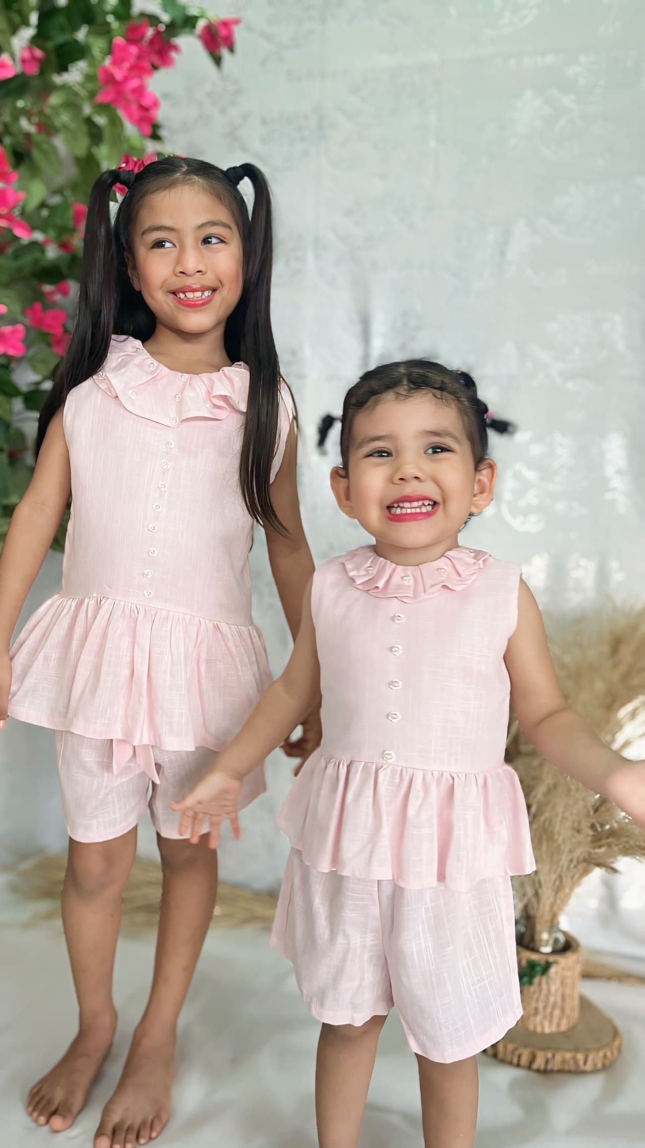 Dos niñas con conjuntos Aurora en tonos rosa, tomadas de la mano